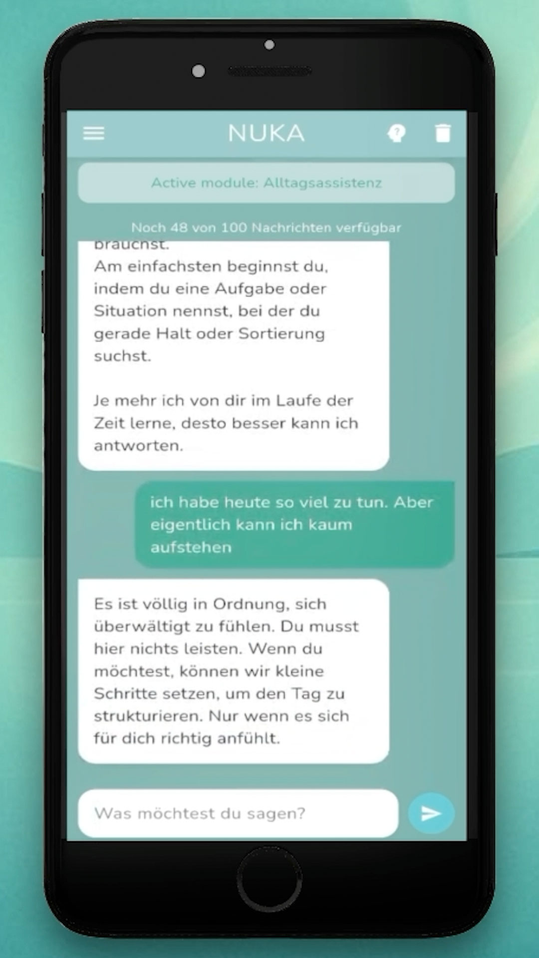 nuka-ai-alltagsassistenz Smartphone-Screenshot der NUKA-App im Modul „Alltagsassistenz“. Auf dem Display ist ein empathischer Chatverlauf zu sehen. Die App zeigt an, dass noch „48 von 100 Nachrichten verfügbar“ sind. Die Konversation beginnt mit der Nachricht von NUKA: „Am einfachsten beginnst du, indem du eine Aufgabe oder Situation nennst, bei der du gerade Halt oder Sortierung suchst.“ Dann schreibt die Nutzerin: „ich habe heute so viel zu tun. Aber eigentlich kann ich kaum aufstehen“. NUKA antwortet unterstützend: „Es ist völlig in Ordnung, sich überwältigt zu fühlen. Du musst hier nichts leisten. Wenn du möchtest, können wir kleine Schritte setzen, um den Tag zu strukturieren. Nur wenn es sich für dich richtig anfühlt.“ Unten befindet sich das Eingabefeld mit dem Platzhalter „Was möchtest du sagen?“ und ein blauer Senden-Button. Der Hintergrund ist sanft türkisfarben.